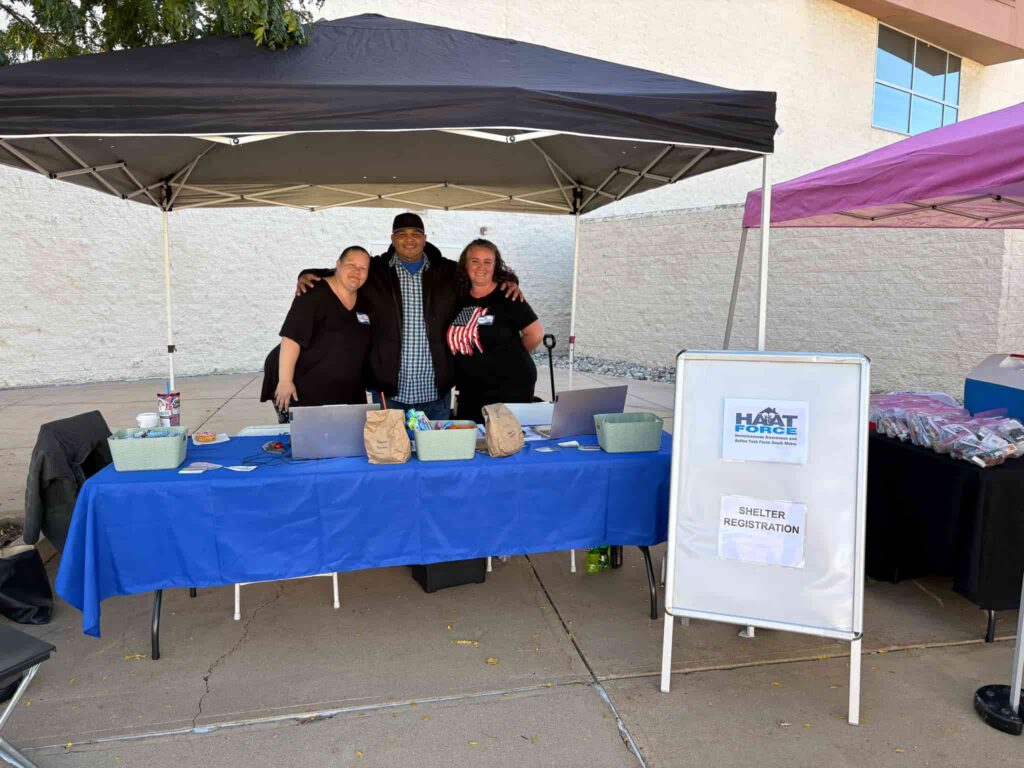 Staff and volunteers standing behind a table preparing for a registration event.